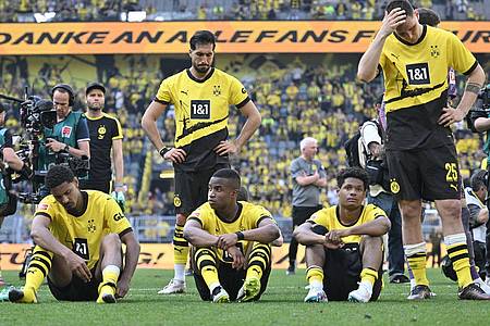 Spieler von Borussia Dortmund sitzen nach dem Spiel enttäuscht auf dem Platz.