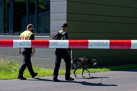 Polizeibeamte ermitteln mit einem Spürhund am Schulzentrum in Lohr am Main, wo der tote 14-Jährige gefunden wurde.
