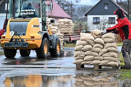 Freiwilligen Helfer verteilen Schleusinger Ortsteil Rappelsdorf in Thüringen Sandsäcke. Foto: Martin Schutt/dpa-Zentralbild/dpa
