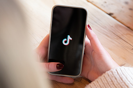 Hand hält Smartphone mit TikTok-Logo auf dem Display